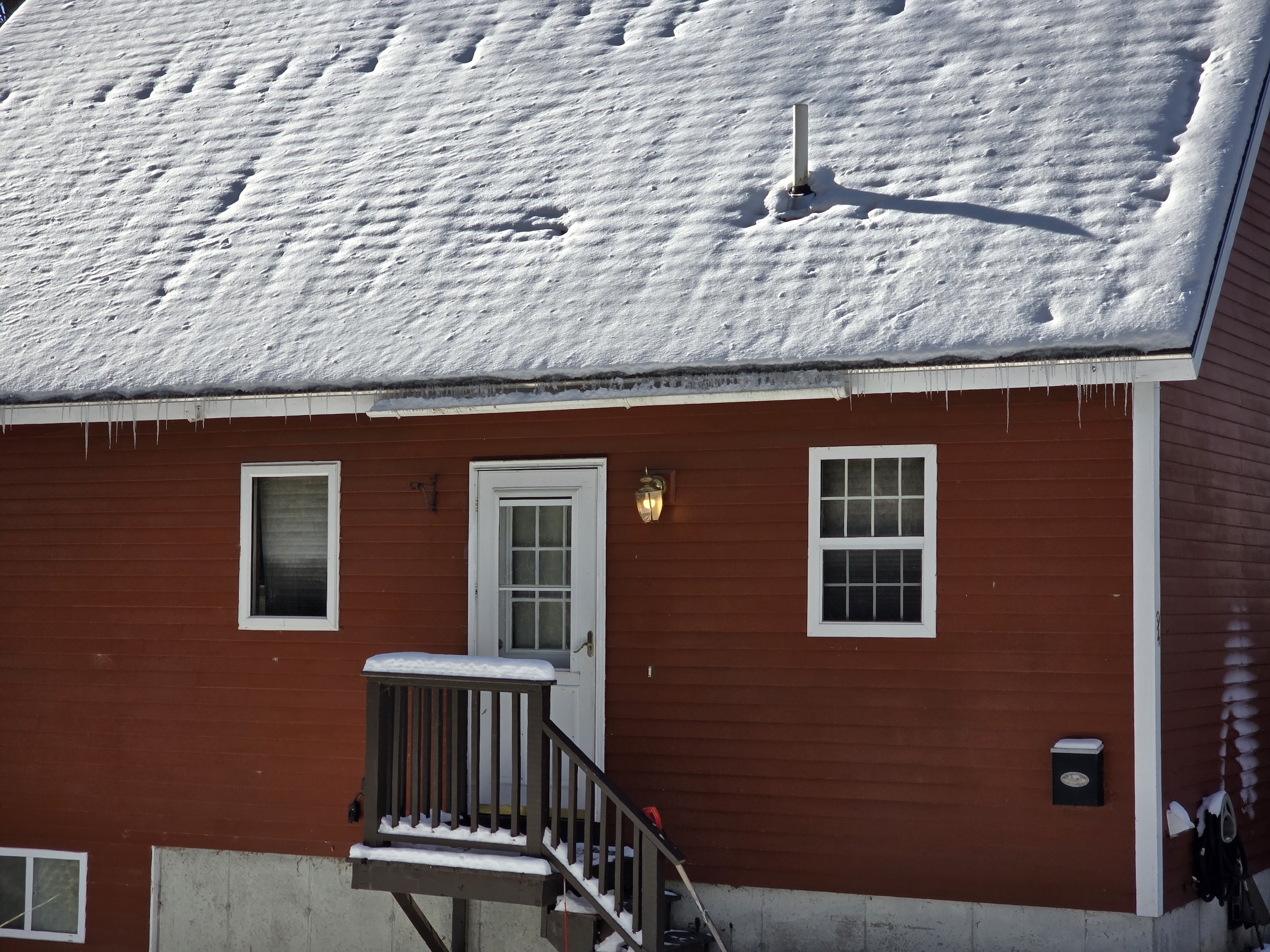Maine house with patchy snow on the roof and icicles on the side of the roof