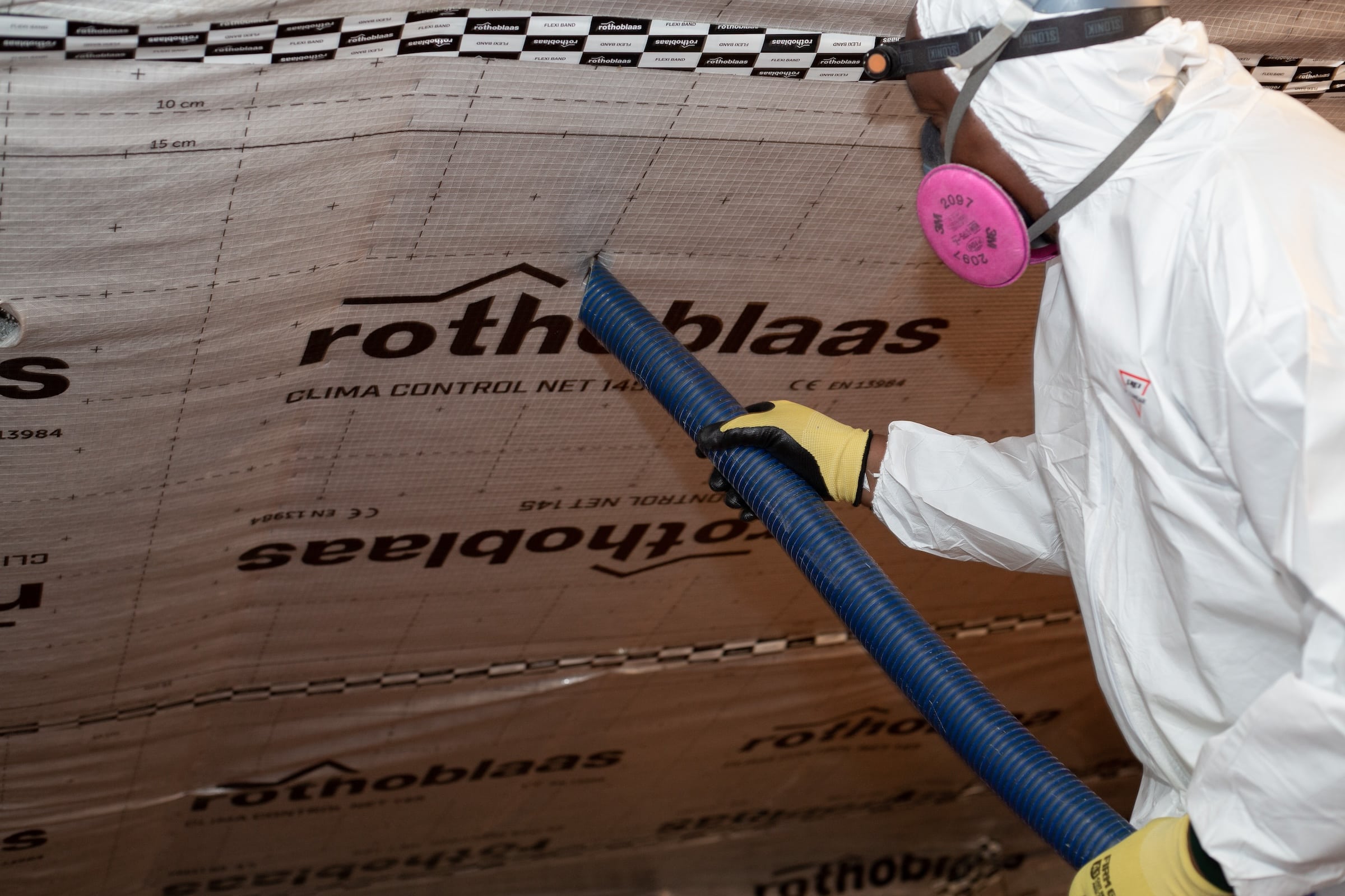 Evergreen team member installing blown insulation in attic