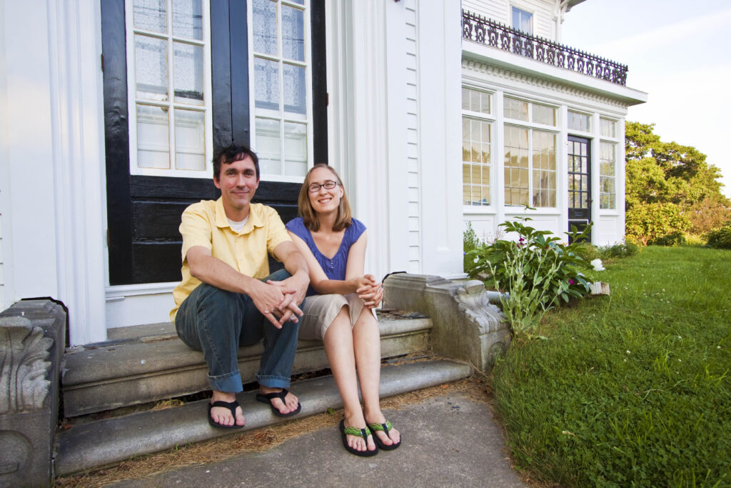 couple smiling in front of their white house