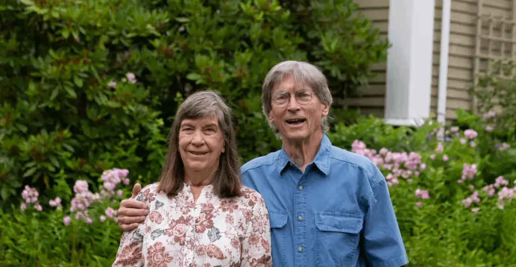 Linda and Sam standing together in their garden, smiling in front of their home after completing an exterior home improvement project